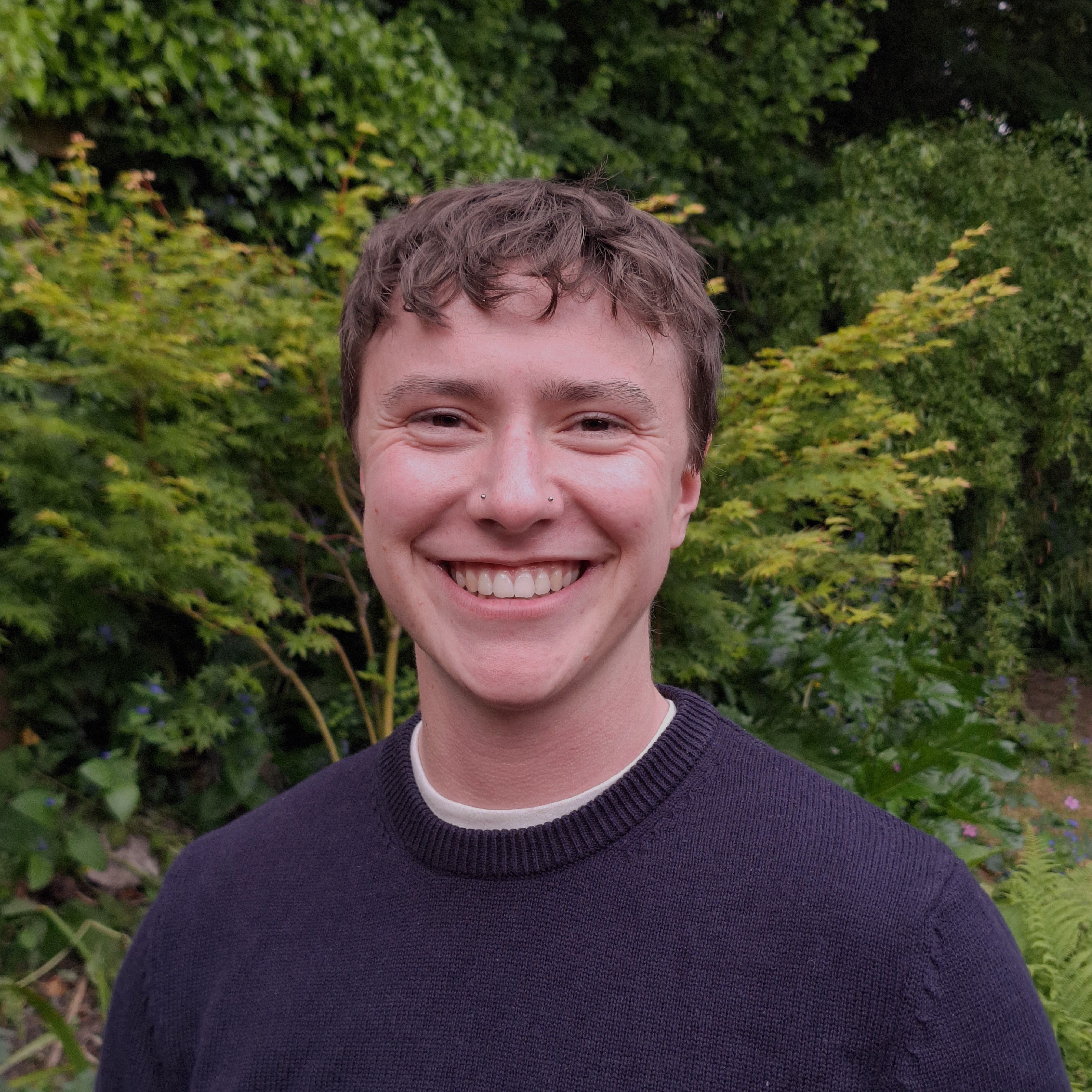 ze smiling at the camera in front of trees